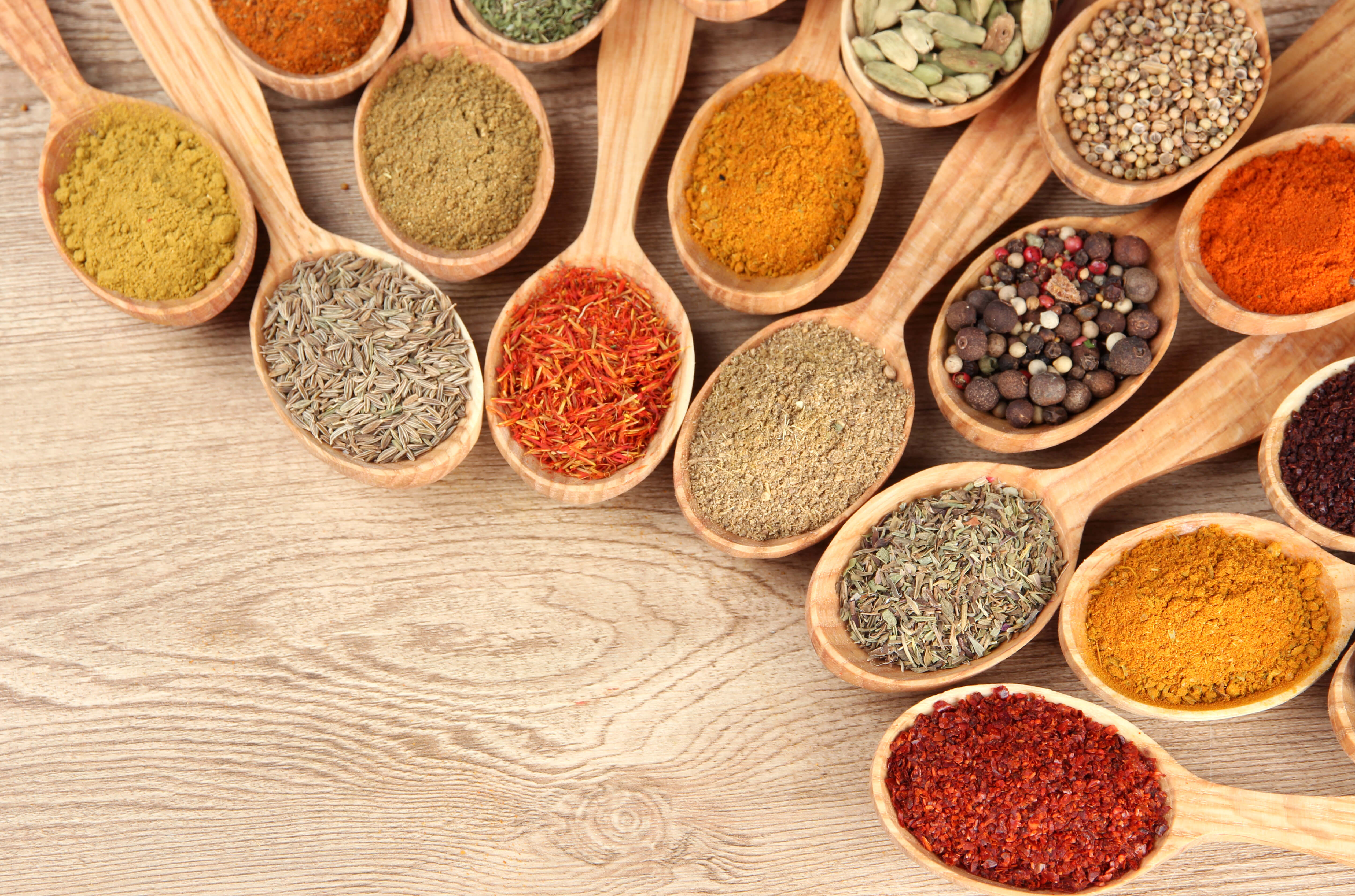 Assortment of ayurvedic herbs in wooden spoons on wooden background